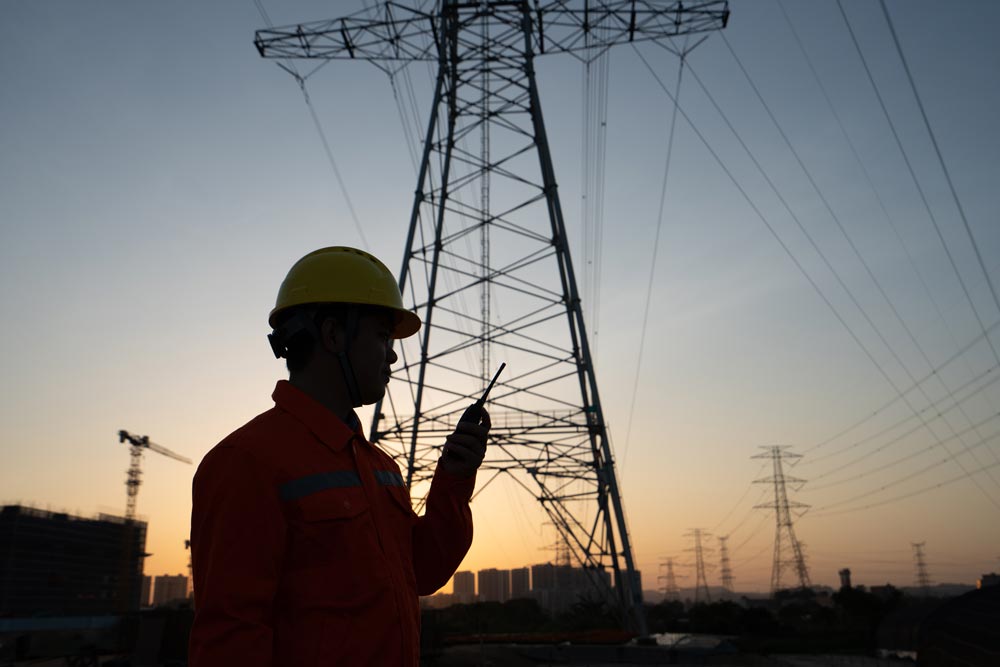 Man som pratar i walkie talkie vid ett elkraftnätverk
